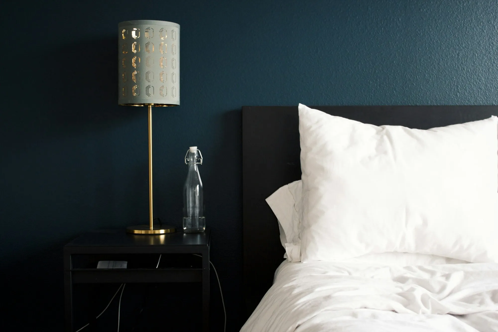 Bedside lamp and white pillows in a dark bedroom