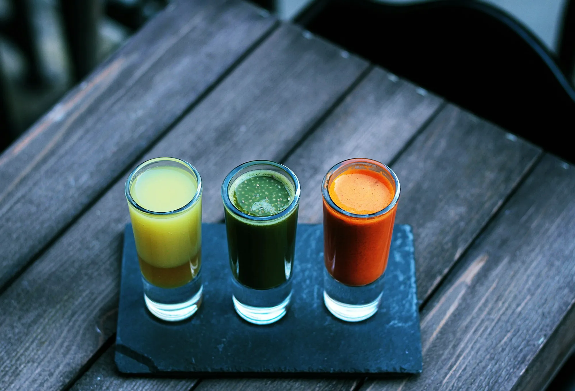 Three drinkable supplement shots in glasses on a slate board